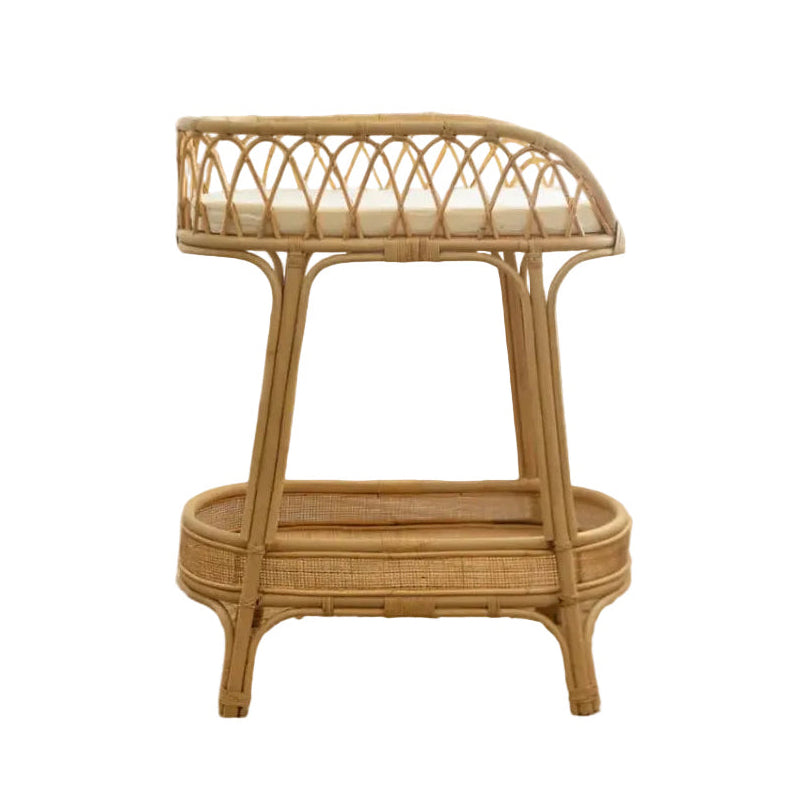 A rattan changing table with a circular frame and a rectangular cushioned top, featuring a woven design pattern.