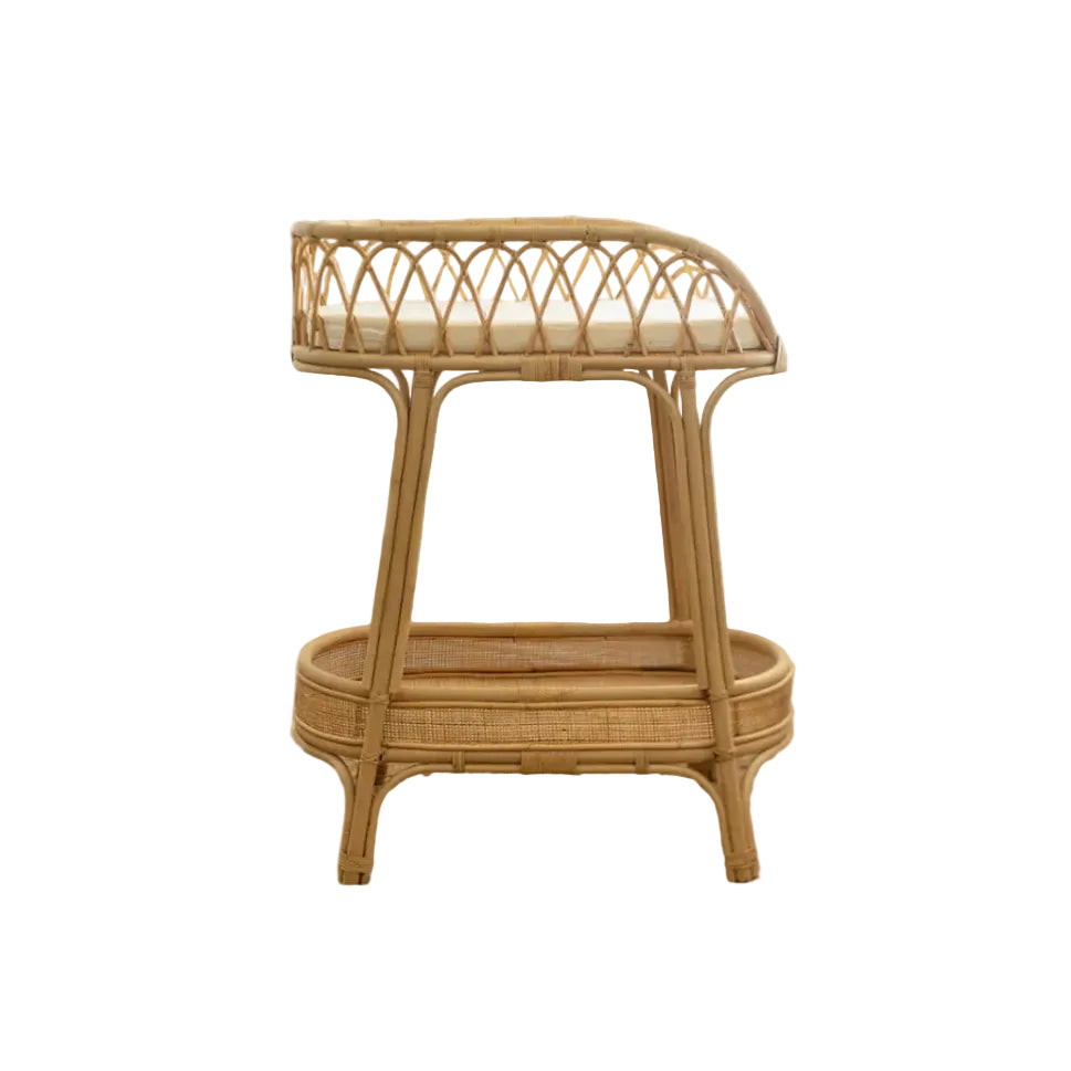 A rattan changing table with a circular frame and a rectangular cushioned top, featuring a woven design pattern.
