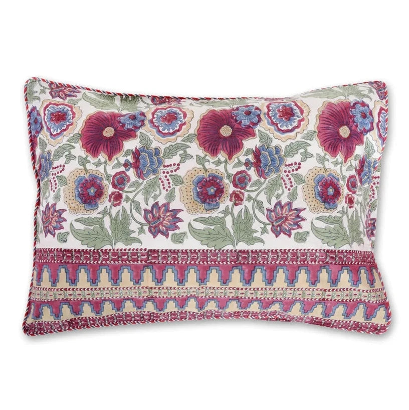 A square decorative throw pillow with a cream background, featuring a vibrant floral pattern in purple, blue, and green, and a textured geometric border in pink and gold along the bottom.