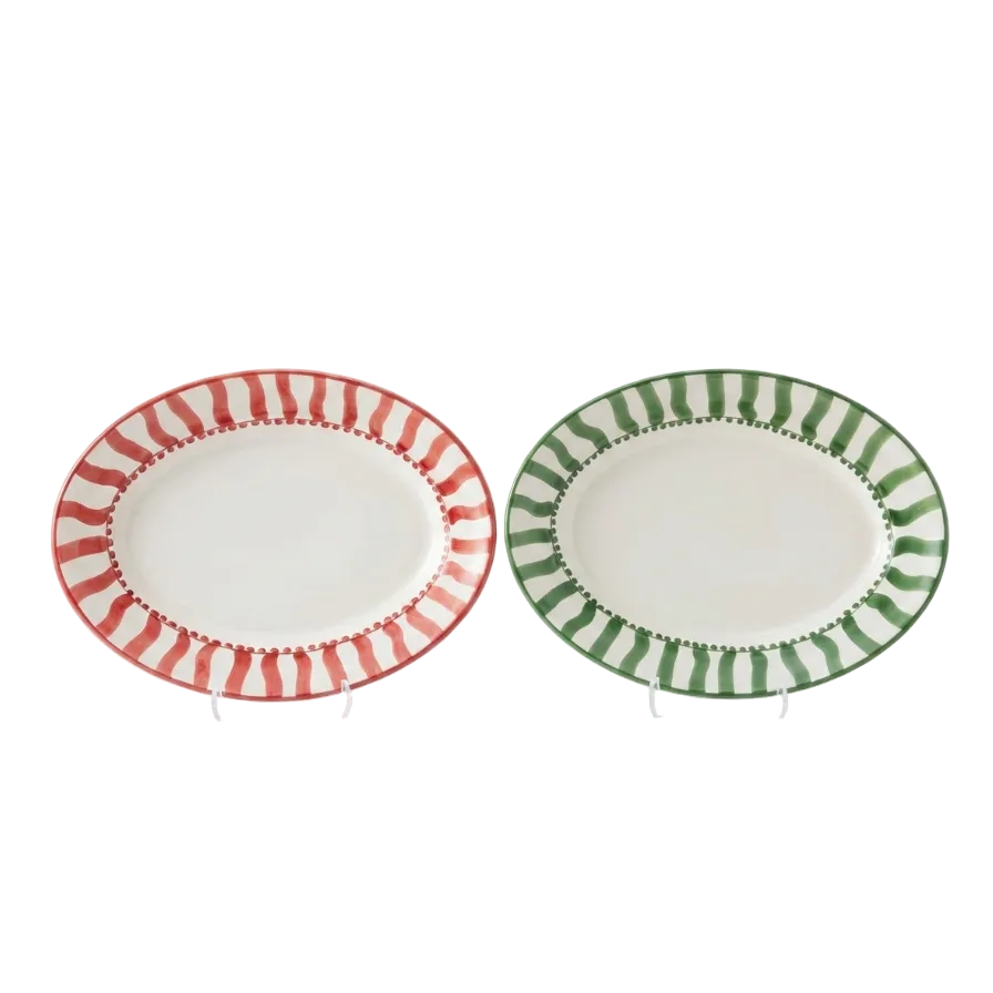 Two oval ceramic serving platters on a white background, one with a red and white striped border and the other with a green and white striped border.