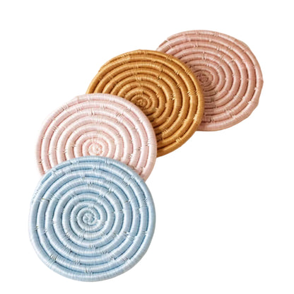 Four circular coasters in pink, blue, and brown on a light background