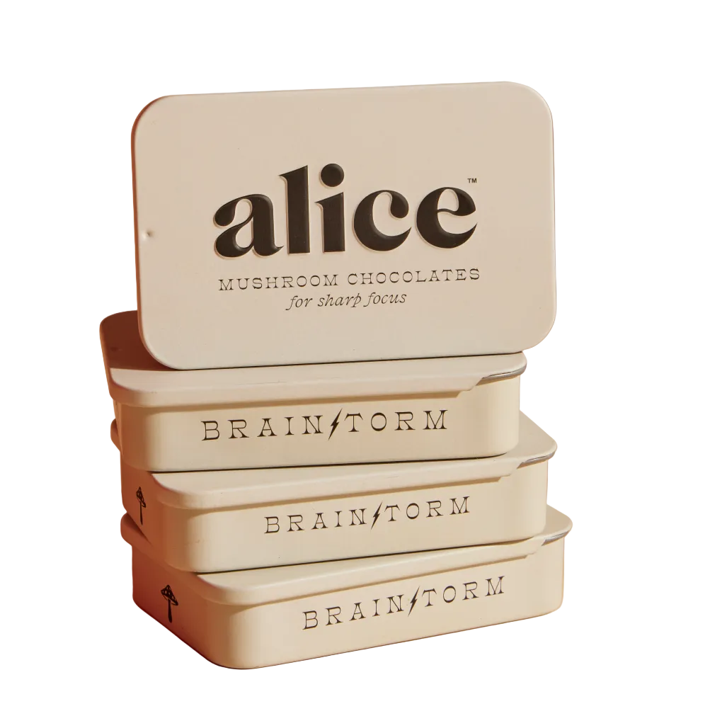 Stack of 'alice' mushroom chocolate tins on a beige background