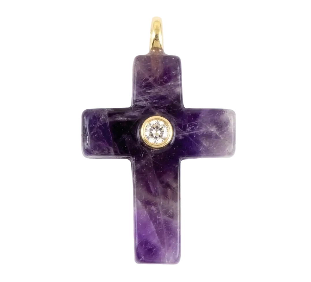 A purple amethyst cross pendant featuring a small gold bezel-set round clear gemstone at its center, with a gold bail at the top, shown on a plain white background.