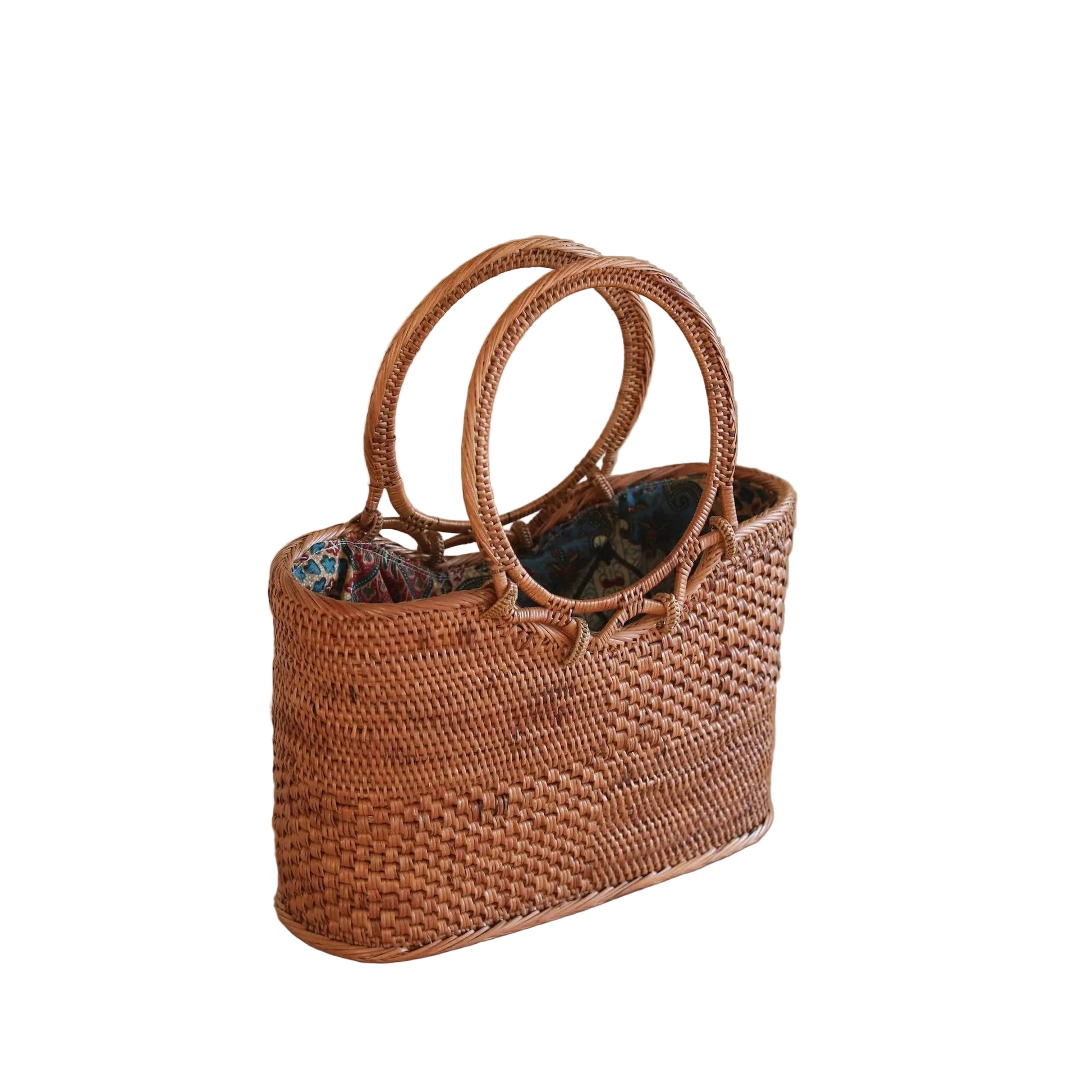Woven handbag on a wooden surface with a plant in the background