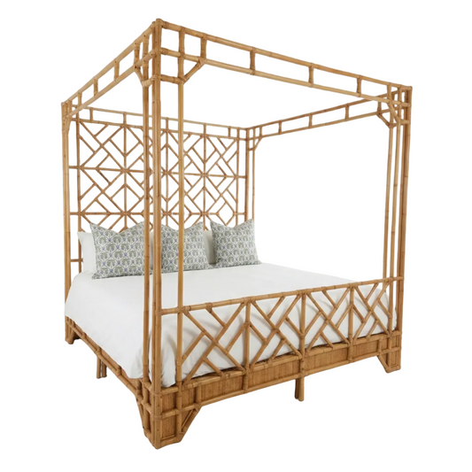 Wicker canopy bed with white mattress and patterned pillows on a white background