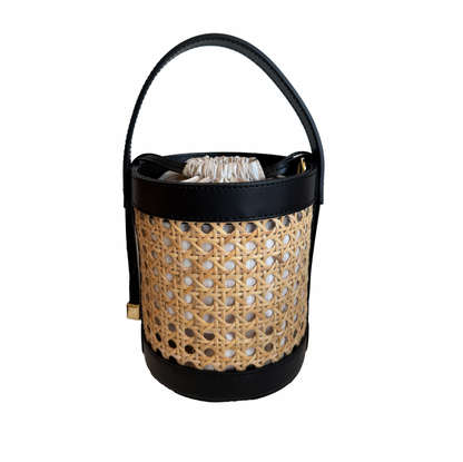 Woven basket with black handle on a white background