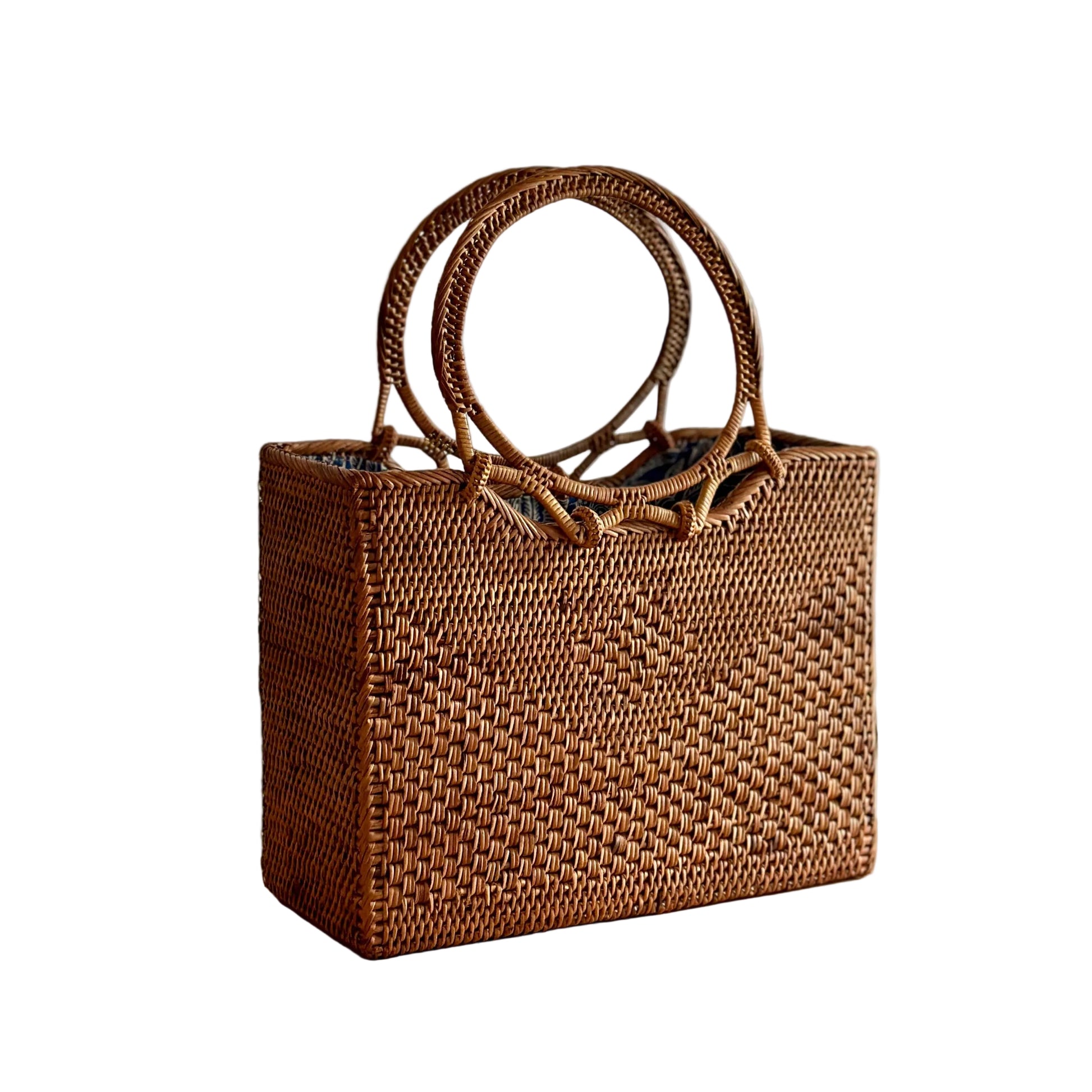 Woven brown handbag with circular handles on a wooden surface