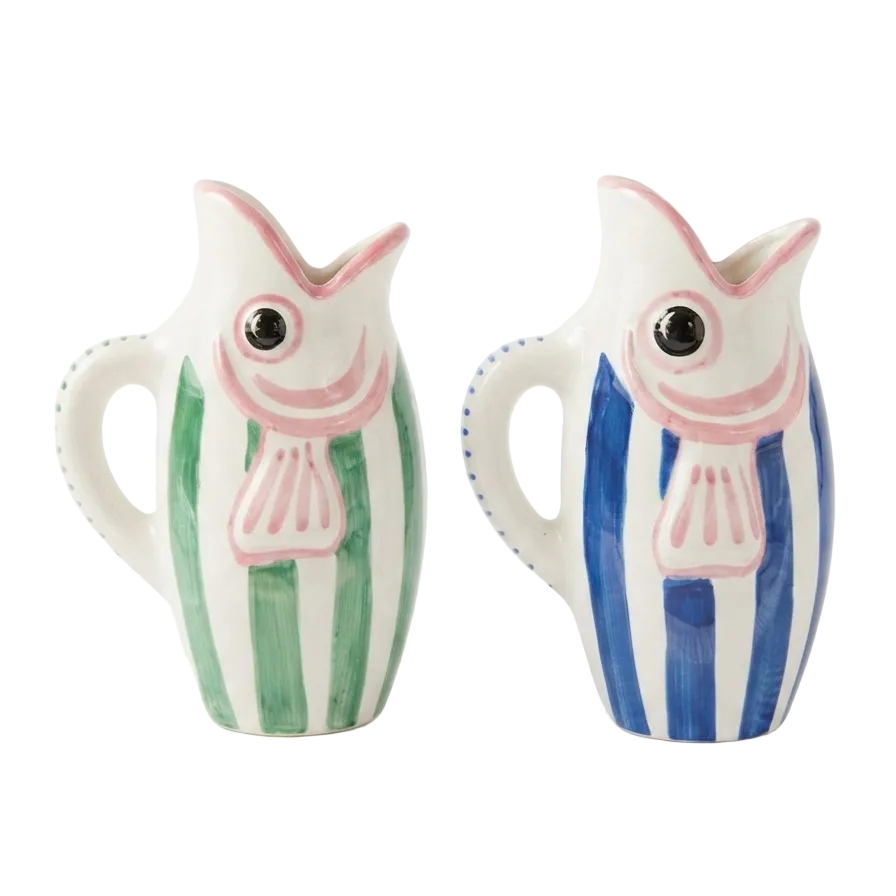Two ceramic fish-shaped pitchers on a white background, one with green and white vertical stripes and pink accents, and the other with blue and white vertical stripes and pink accents.