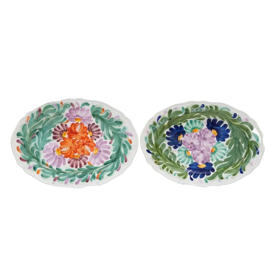 Two oval white ceramic serving platters with hand-painted floral designs, displayed side-by-side on clear plastic stands against a white background.