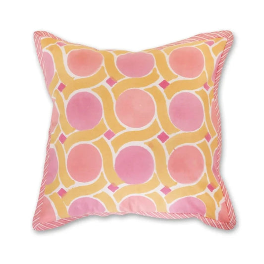 A square throw pillow with a pink and yellow geometric pattern, featuring a pink rope fringe along the edges, shown against a plain white background.