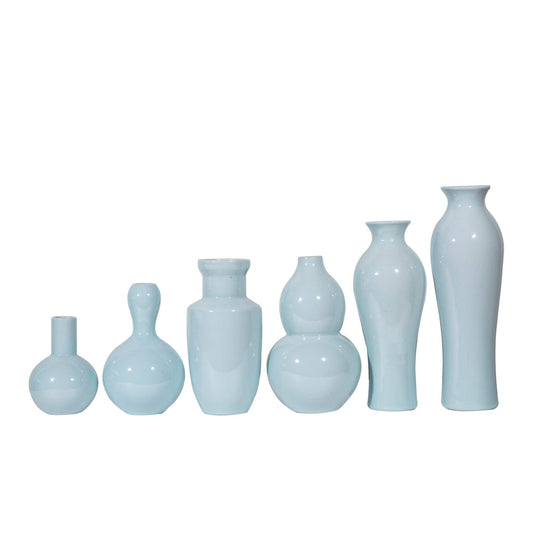 Set of light blue ceramic vases of various shapes on a white background