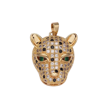 A gold-toned leopard head pendant covered in pavé-set clear and black stones, with green stone eyes, shown on a plain light background.