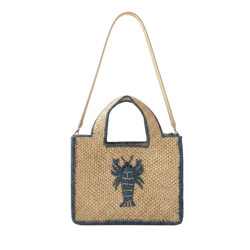 A woven straw tote bag with a navy blue lobster graphic on the front, a navy blue trim, and a matching woven shoulder strap, shown against a plain white background.
