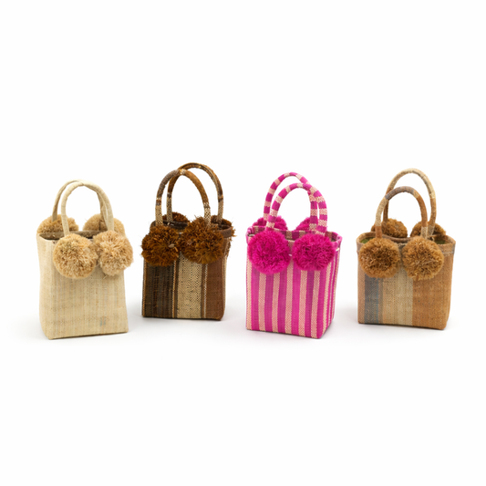 Four small handbags with pom-pom details on a white background