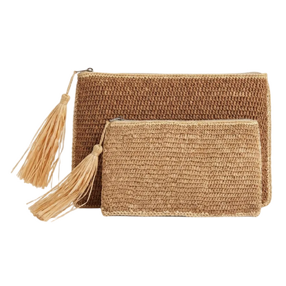 Two woven straw clutch bags in natural tan and light beige, featuring a larger rectangular bag and a smaller zippered pouch, both with matching tassels, set against a plain white background.