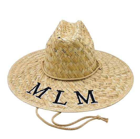 A natural woven straw cowboy hat with a wide brim, featuring the embroidered letters 'MLM' in black on the brim and a matching rope chin strap, shown on a white background.