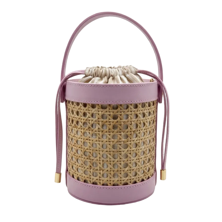 Woven bucket bag with pink leather handle and base on a white background