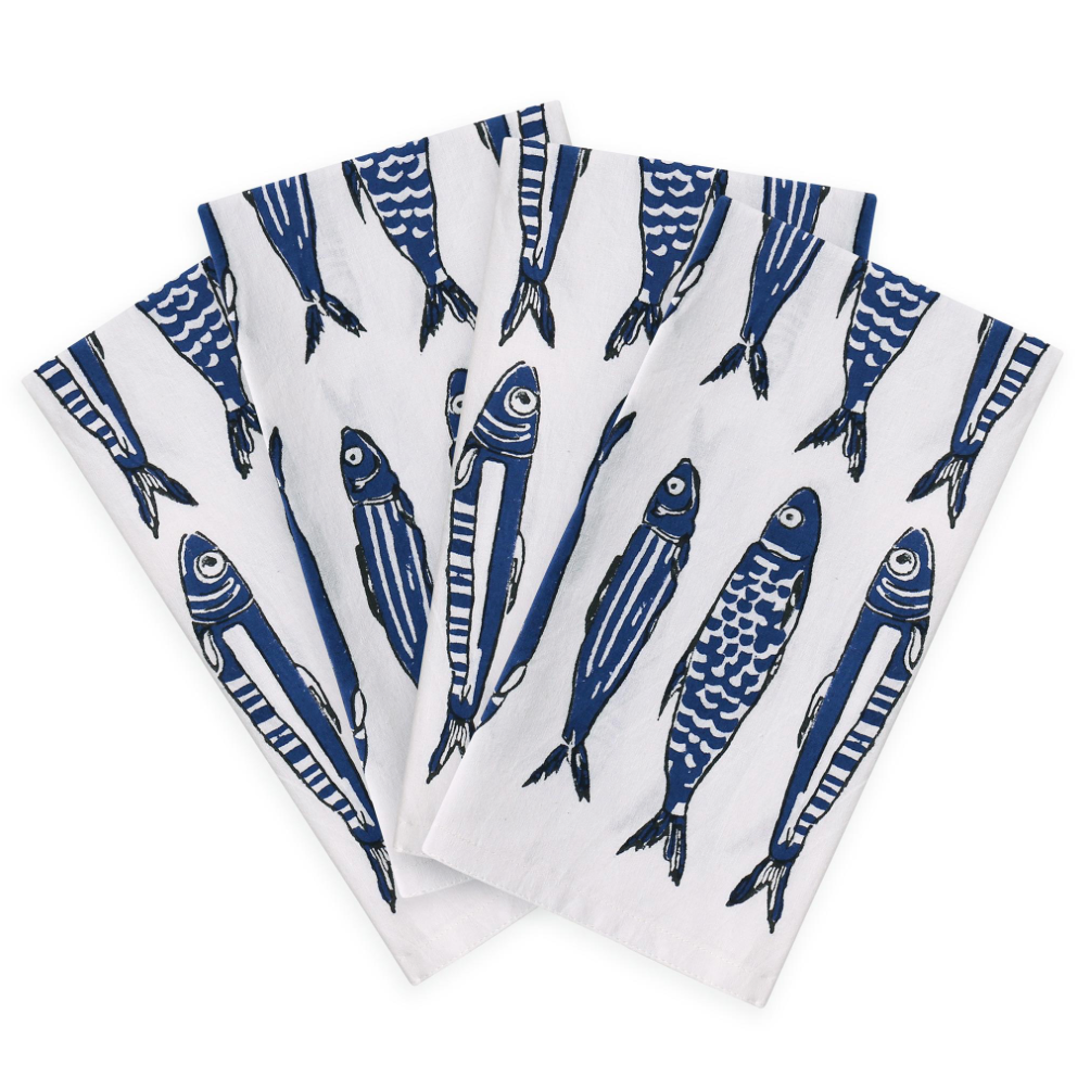 Three white table napkins with a blue fish pattern, fanned out on a white background.