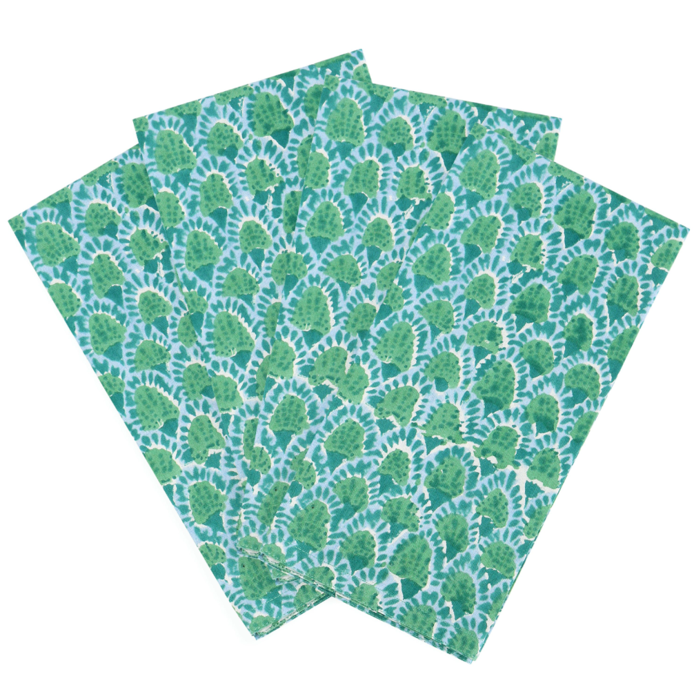 Three square fabric napkins with a green and blue tie-dye scallop pattern, arranged overlapping on a white background.