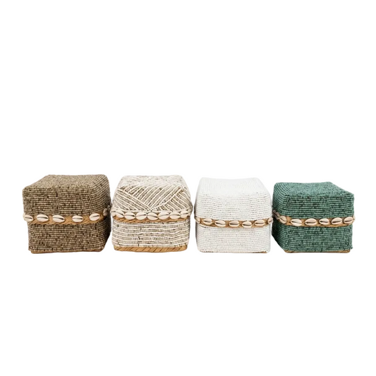 Four small woven decorative boxes lined up on a white background, featuring natural brown, cream, off-white, and teal-green woven patterns with shell-like accents around the middle.
