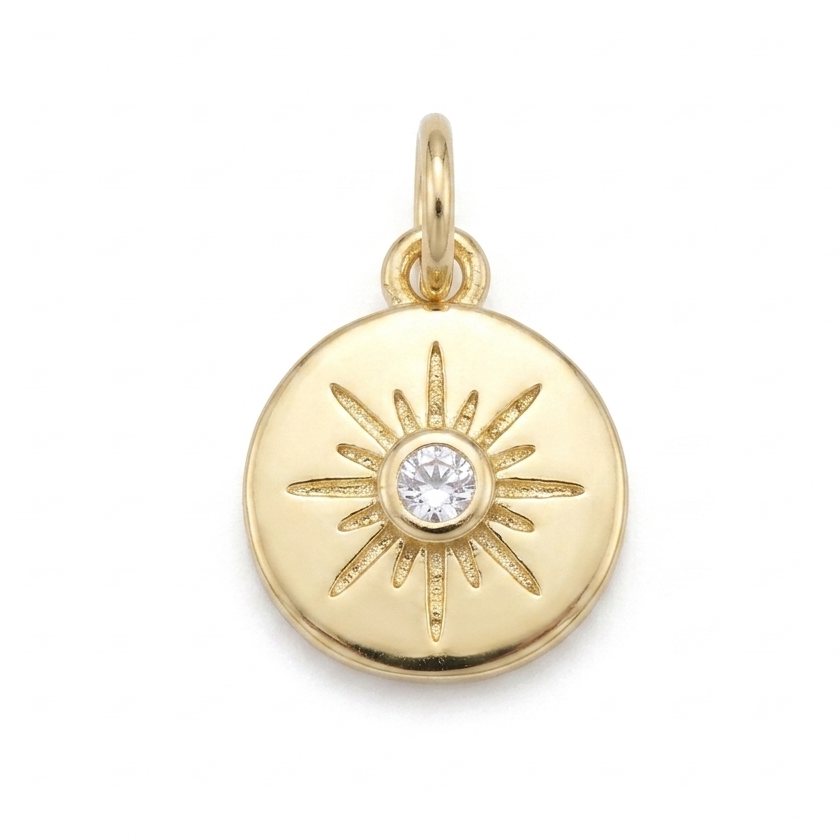 Gold pendant with sun design and diamond center on a white background