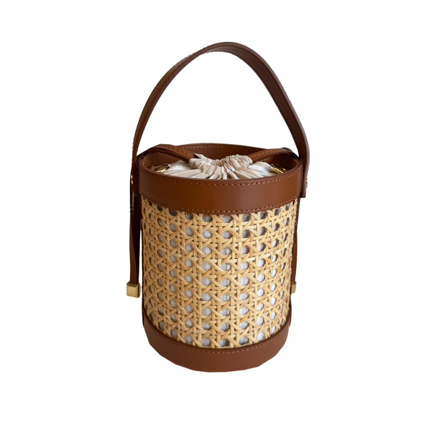 Woven basket with brown leather handle and trim on a white background