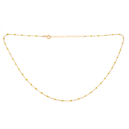 Gold necklace with small yellow beads on a white background